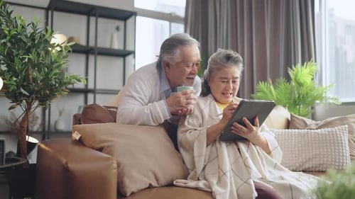 Loving Senior Couple Relaxing at Home with Tablet