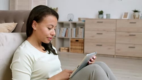 Woman Sitting on Floor Using Tablet Indoors