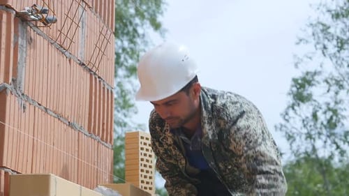 The Builder Puts a Brick By Using Cement on Building