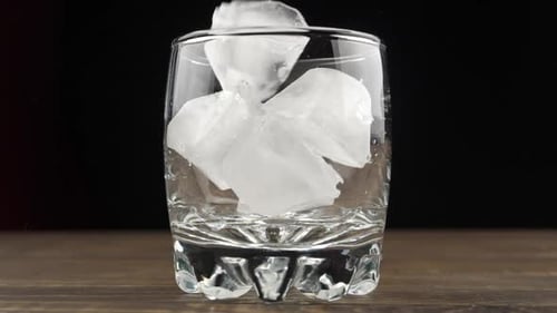 Ice cubes fall into a glass, slow motion. Cocktail concept.