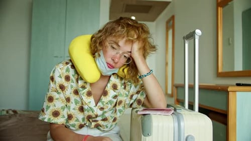 a Woman in a Hotel Room Wearing a Protective Mask and with a Suitcase Immediately After the Airport