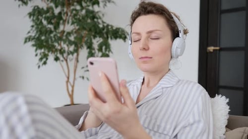 Woman Lounging with Phone and Headphones at Home