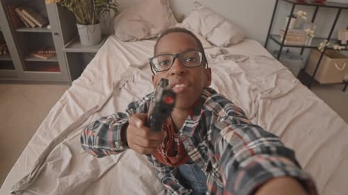 Young Boy Aims Toy Gun in Bedroom