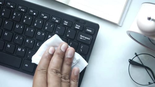 Hand Cleaning Black Keyboard with a Wipe