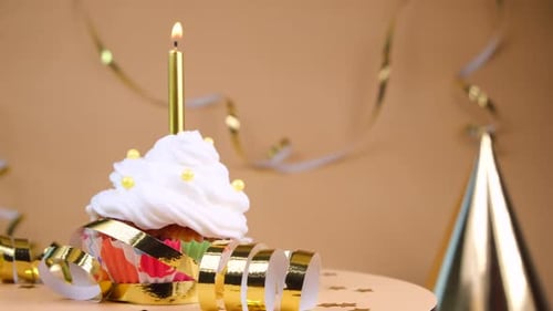 Celebratory Cupcake with Candle and Gold Decorations