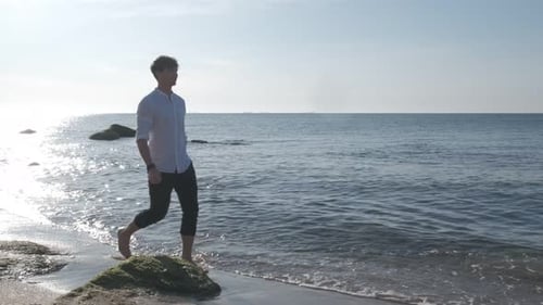 Guy Walking On The Sea Beach At Sunrise