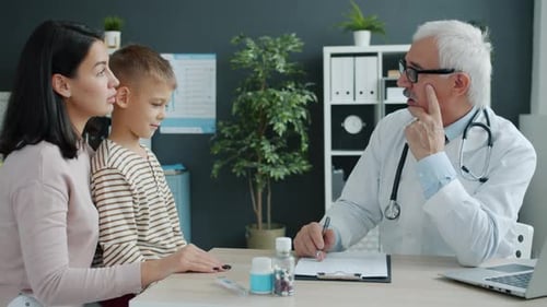Mother and Child Talking To Doctor During Appointment in Children's Hospital