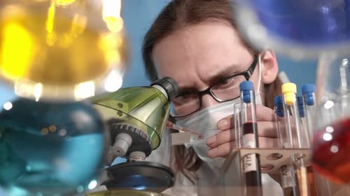 Scientist Drops Orange Liquid Pipetting Red Liquid Onto Microscope Stand