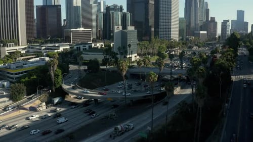 AERIAL: Toward Downtown Los Angeles, California Intersection Traffic with Palm Trees and Skyline in