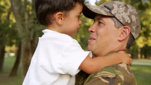 Heartwarming Moment: Soldier and Child Embrace in Park