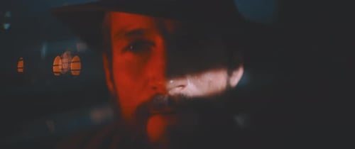 Close up of man through shutters and red lights using vintage camera