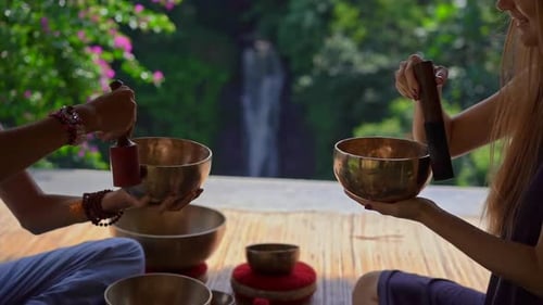 Adults Meditating with Singing Bowls near Waterfall