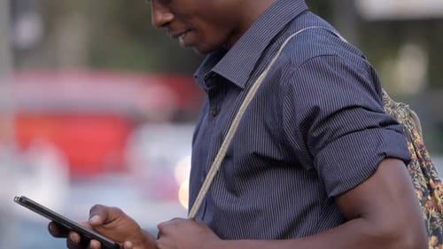 Young black african man typing on his smartphone in the street- slow motion