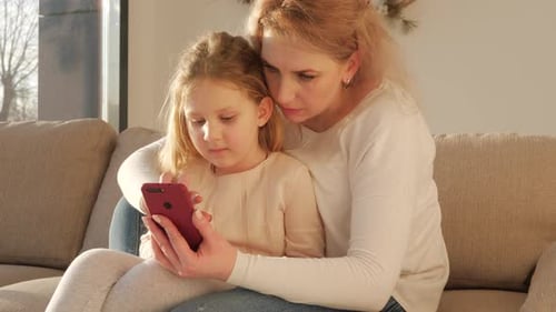 Woman and Child Looking at Smartphone on Couch