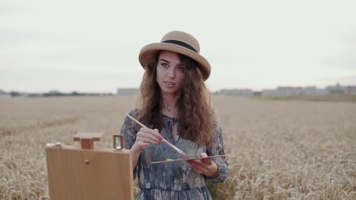 Happy Paintress Painting Landscape on Canvas Among Ripe Wheat Field with Horizon
