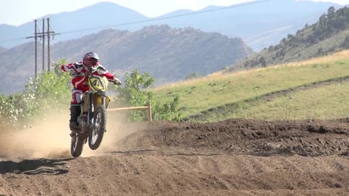 A young man riding a motocross dirt motorcycle.