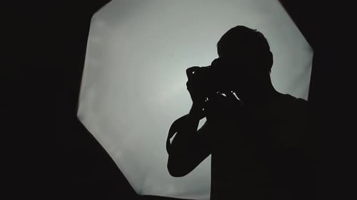 Photographer is Taking Pictures in the Studio on a Softbox Background Closeup Silhouette