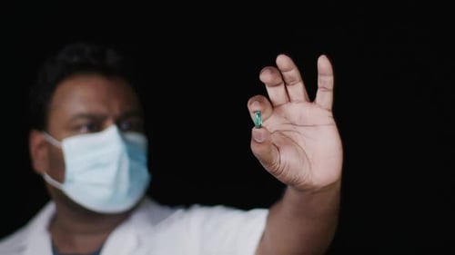 Lab Technician Holds Green Capsule