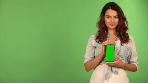 A Caucasian Woman Shows a Smartphone with Green Screen to the Camera with a Smile Green Screen