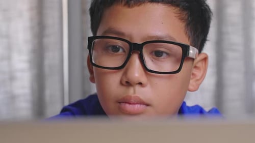 Boy Wearing Glasses Using Laptop Computer at Home