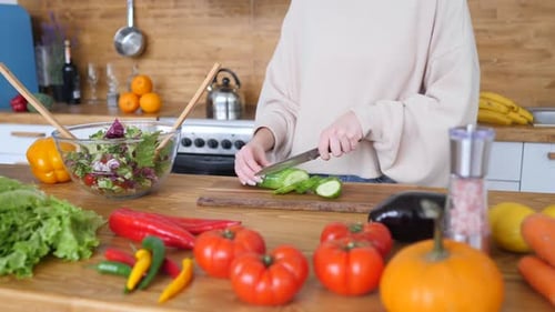 Woman Cutting Fresh Vegetables For Healthy Green Salad In Kitchen.