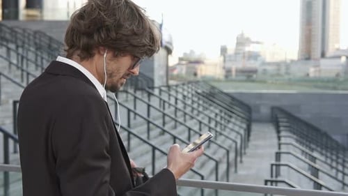 The businessman went out for a coffee break and works on a smartphone.