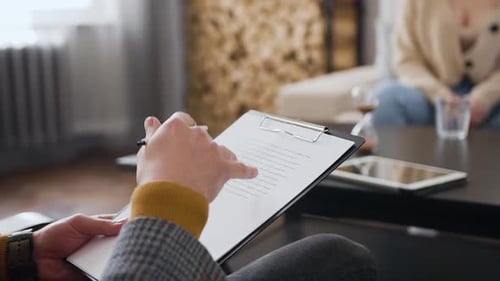 Homme qui est assis sur une chaise, tenant un dossier avec des notes principales pour lui