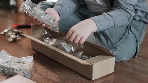 Les mains du garçon sortent les raccords pour l'assemblage de meubles de la boîte en gros plan