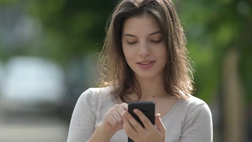 Smiling Woman Uses Phone Outdoors