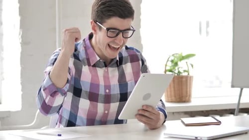 Man Celebrating Success with Tablet in Office