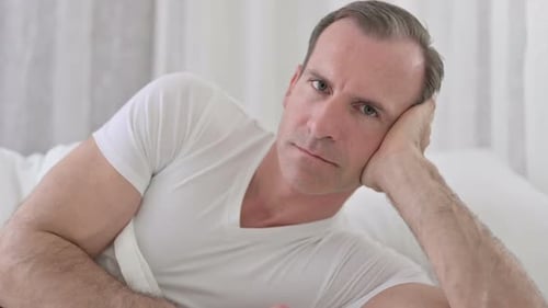 Close Up of Middle Aged Man Looking at the Camera in Bed