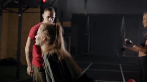 The Coach's in the Gym. A Man Shows Exercises To Two Young Women. Blondes Learn the Right Technique