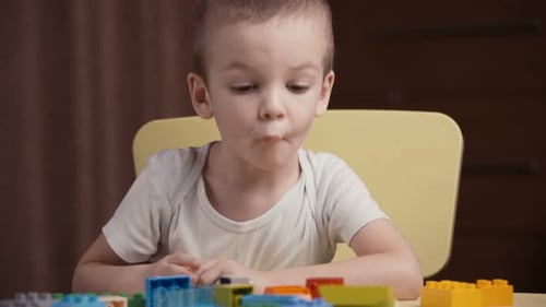 Footage Kleiner glücklicher Junge spielt mit bunten Blöcken eines Konstrukteurs zu Hause