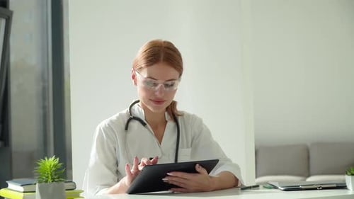 Woman Doctor Using Tablet at Her Desk