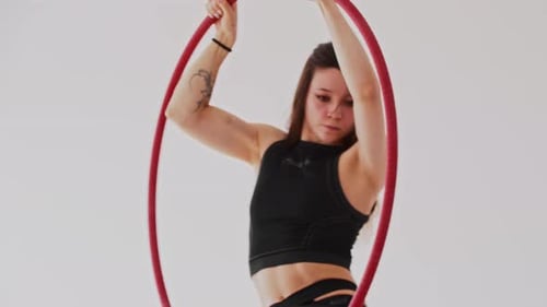 Young Gymnastic Woman with a Tattoo Spinning on the Acrobatic Ring in the White Studio