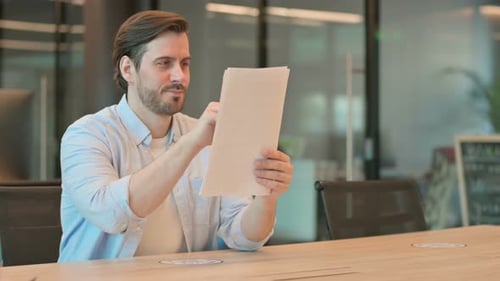Man Reviewing Paperwork at Office Desk