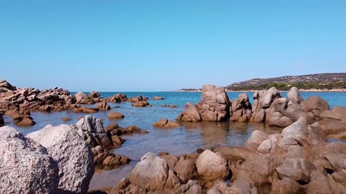 Drone shot of a wild beach. Zoom in shot moving from the beach, between the rocks to the open sea.