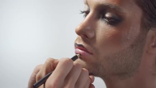 Appliquer un crayon à lèvres noir sur un bel homme