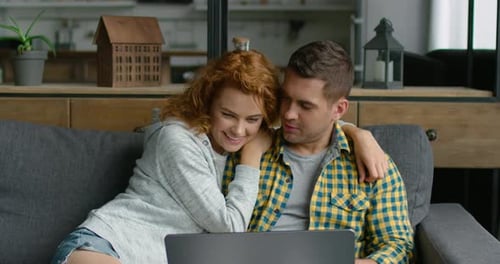 Loving Couple Using Laptop on Couch at Home