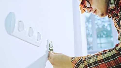 Electrician Connecting Wires to Outlet in Home