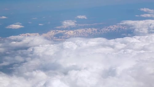 Aerial View of Snow-Capped Mountains Over Clouds