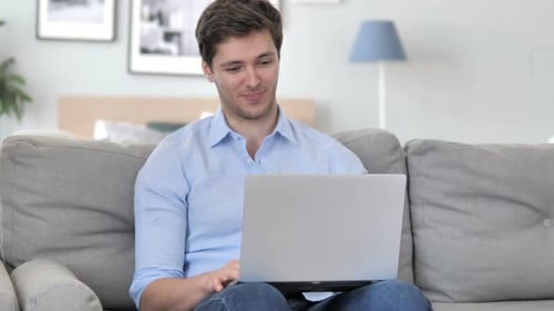 Man Waving During a Video Call on Laptop