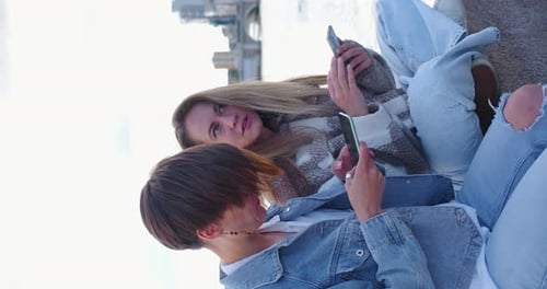 Young Adults Relaxing With Smartphones in City