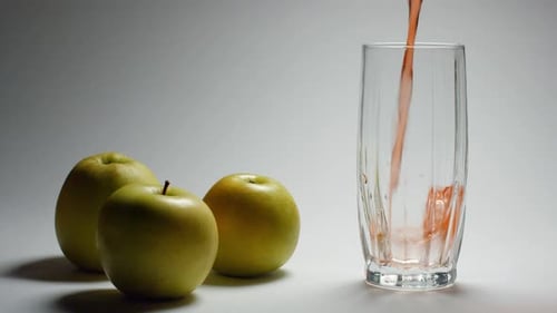 Red Juice Being Poured Next to Fresh Apples