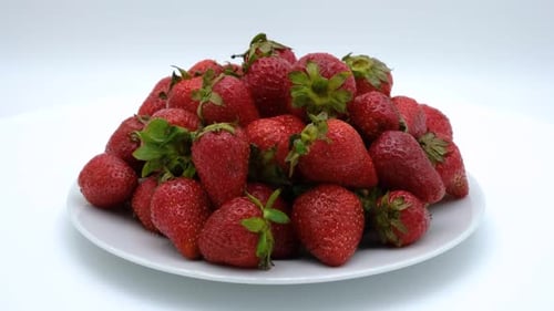 Strawberries on a plate rotating on a white background. Strawberry ripe season