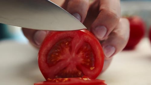 Professional restaurant kitchen, close-up: Chef cuts tomatoes with a knife