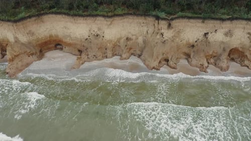 Aerial View of Ocean Waves Beating Against a Rocky Shore on a Wooded Tropical Seaboard
