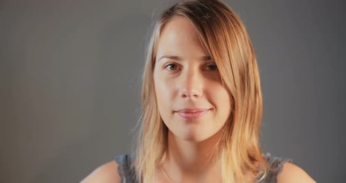 Close up of a young blond woman smiling on white studio background