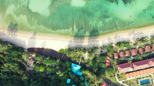 Holiday resort with villas built alongside white sandy beach washed by calm clear water of turquoise