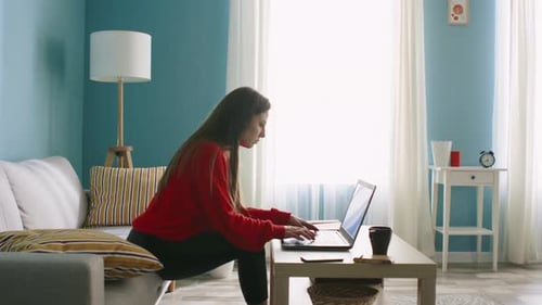 Woman Using Laptop and Drinking from Mug Indoors